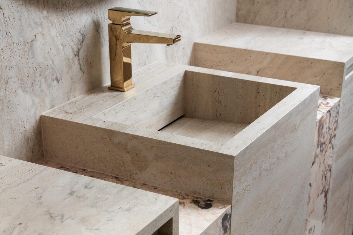 Travertine stone vanity with polished brass faucet, showroom interior